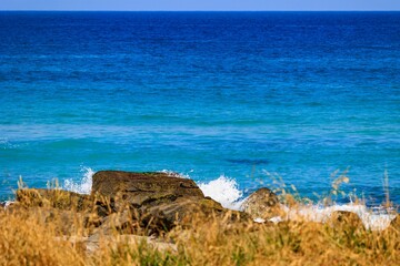 Scenic beach scene featuring a rocky shoreline with blue waters in the background