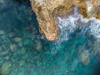 aerial view of the water of the Mediterranean Sea contrasting its movement with the firmness of the rock.