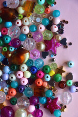 Various colorful beads on bright pink background. Top view.