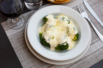 Appetizing broccoli and cauliflower gratin garnished with cheese and cream served on white plate...