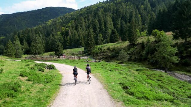 Two cyclists are riding gravel bikes in the scenic beauty of the mountains.Cycling on gravel roads or off-road.Active adventures and the concept of travel by bike.Gravel bike riding in nature.