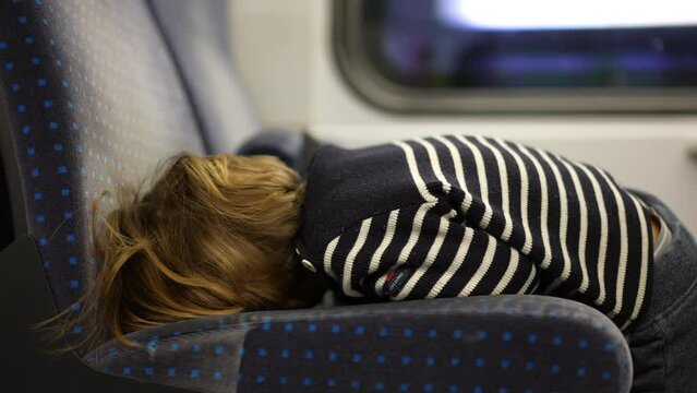 Back of bored child leaning on train chair with nothing to do while on travel commute