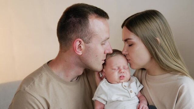 Caring and loving parent kiss their sleeping baby on the head. Beautiful family of three portrait.