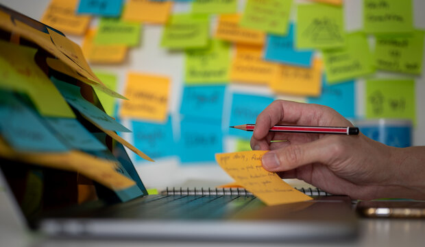 blurred colorful post note background, man using pencil and computer laptop working on memo note memorandum in office, reminder messages for working schedule, things to do list - Powered by Adobe