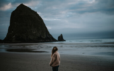 woman looking at haystack rock on a gloomy day