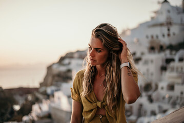 A Woman playing with Hair with Santorini, Greece in the background - obrazy, fototapety, plakaty