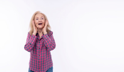 Excited surprise grandmother raised hands on face smiling joyful looking camera over isolated white background.Shocked winner healthy mature elderly woman holding hands beside mouth looking copy space