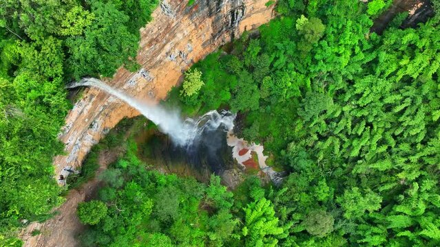 A mesmerizing forest drone shot captures a majestic waterfall cascading from a towering cliff, a symphony of nature's beauty and power. (Nam Nao Canyon, Nam Nao National Park, Thailand). Aerial view.
