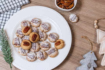 Obraz na płótnie Canvas Christmas cookies with nuts on a plate on a wooden table