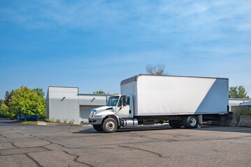 Valuable day cab rig semi truck with extended box trailer for local freights standing on the...