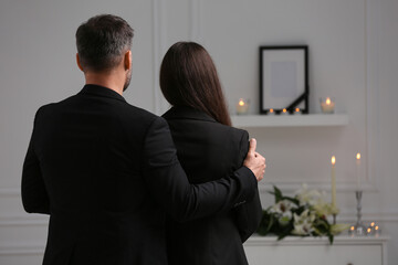 Couple mourning indoors, back view and space for text. Funeral ceremony - obrazy, fototapety, plakaty