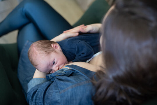 Mother breastfeeding newborn baby looking at her