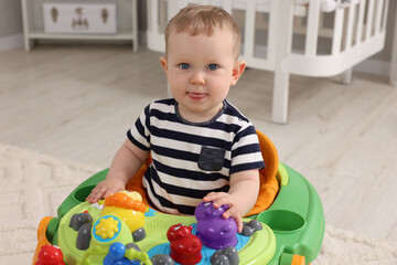 Portrait of cute baby with toy walker at home. Learning to walk