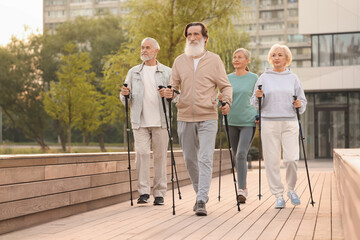 Group of senior people performing Nordic walking outdoors. Low angle view