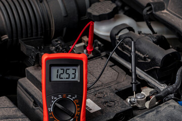 Battery tester checking car battery voltage. Vehicle maintenance, repair and service concept.
