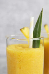 Tasty pineapple smoothie on light gray background, closeup