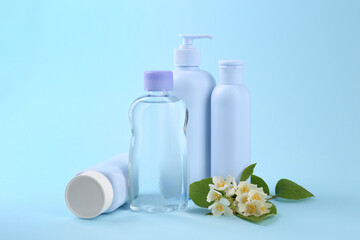 Baby care products and beautiful flowers on light blue background. Space for text