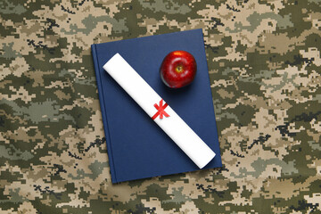 Notebook, apple and diploma on camouflage background, top view. Military education