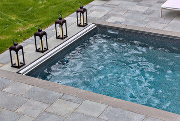 outdoor pool detail (backyard swimming pool with candle holder lanterns, lounge chairs, stone granite) summer swimming, leisure, luxury yard, hotel, party - Powered by Adobe