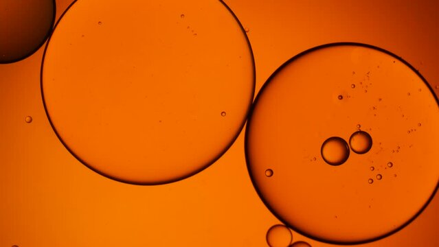 Gold artistic of oil drop floating on the water. Pastel color bubble for background. Orange background of oil drop.
