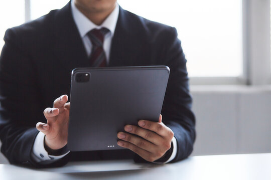 タブレット端末を見ているスーツを着た男性