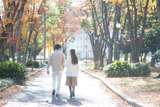 晩秋の並木道を散歩する20代カップル
