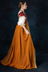 Fototapeta premium Woman wearing a Renaissance, Tudor, Georgian, or high fantasy costume with a red embroidered bodice and a pearl choker