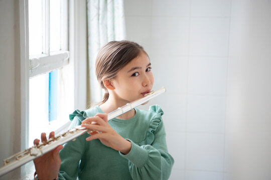 窓辺でフルートを吹いている女の子