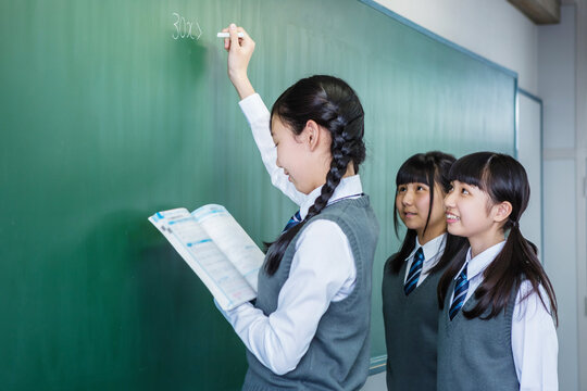 黒板にチョークで書く女子中学生