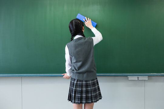 黒板にチョークで書く女子中学生