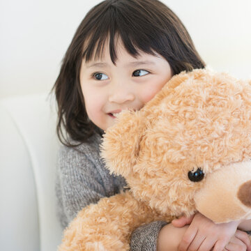 クマのぬいぐるみを持ち微笑む女の子