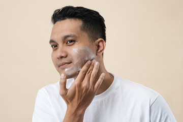 Photo of a young Asian man with cream for problem skin applied onto the face, close-up concept.
