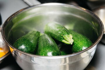 zucchini in a serving stainless steel bowl on the table in the kitchen