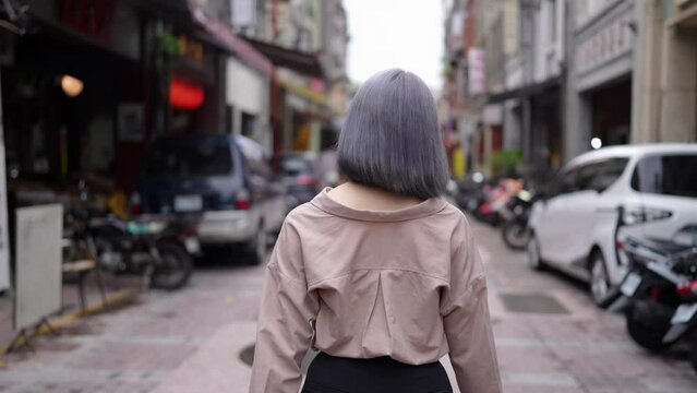 灰色の髪の若い台湾人女性が油化街の古い町並みを散策するスローモーション映像 Slow motion video of a young Taiwanese woman with gray hair strolling through the old streets of Dihua Street.