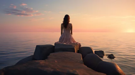 Foto op Plexiglas Woman sitting on a breakwater and looking at the horizon © tashechka