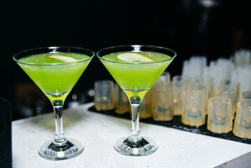 Green cocktail in a martini glass on a bar counter in a nightclub