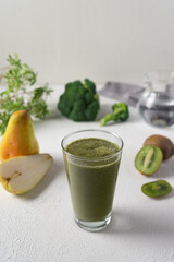 Glass of fresh green smoothie with kiwi, pear and broccoli on white background
