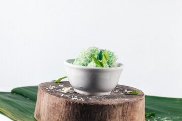 A bunch of Klepon Cakes in a white bowl with grated coconut.. Sweet ball-shaped rice cakes with palm sugar. Isolated white background. Jajan Pasar
