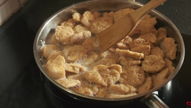Cooking vegan TVP Textured Vegetable Protein in a pan, in slow motion 4K