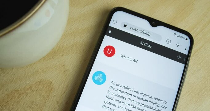 Artificial Intelligence - AI chat bot app on smartphone - Royalty free phone and app interface - Close shot, coffee - "What is AI?"