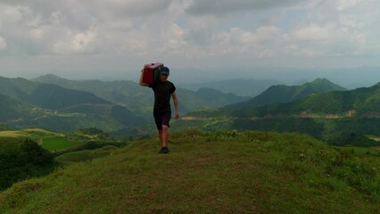 Funny creative scene of male carrying old TV walking on mountain in slow motion