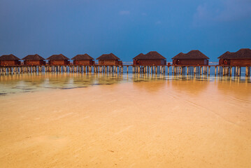 Maldivian bungalows in sunset light on a stormy evening