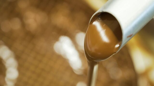 Closeup shot of creamy chocolate flowing through a pipe at a cake-making factory