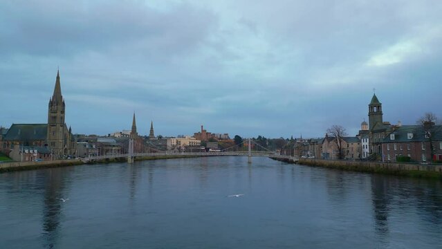 Forwards fly above Ness river with its bridges in historic city centre in Inverness. Aerial view of sights on waterfronts. Scotland, UK