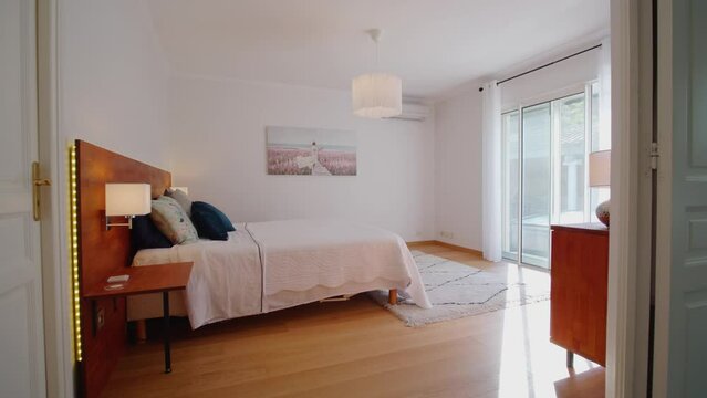 Slow revealing shot of a bedroom with a large patio door with an outside pool