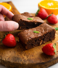 Chocolate brownie cut into portions and decorated with strawberries and mint.