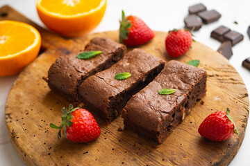 Chocolate brownie cut into portions and decorated with strawberries and mint.