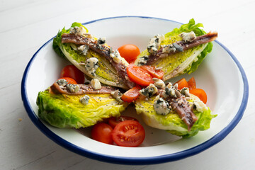 Fresh lettuce heads with an anchovy and cherry tomatoes.