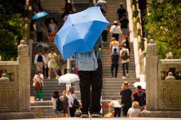 A woman holding a blue umbrella, praying forward