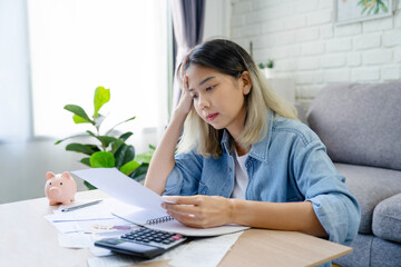 Asian woman with a calculator in the living room. A serious lady with calculates finances and...